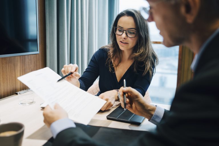 Male and female entrepreneur brainstorming over document during meeting in office